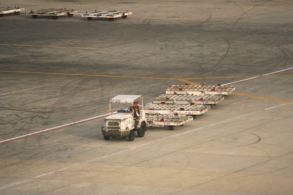 공항 활주로에서 화물 카트를 견인하는 차량을 위에서 내려다본 모습